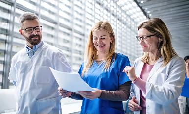 Three healthcare professionals reviewing documents together in a bright modern medical facility.